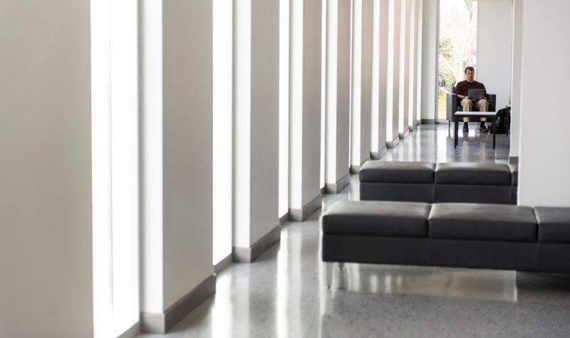 Student studying at the end of a long corridor